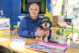 Mann mit Hund an einem Tisch im Freien sitzend 